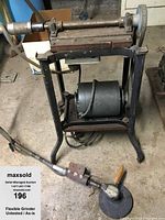 Side view of old electric flexible grinder showing cast iron frame, motor at base and flexible shaft.