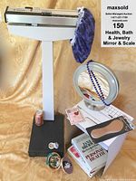 Full lot overview with floor scale, lighted mirror, insoles, books, and jewelry on a yellow fabric backdrop; soda can included for size comparison (not included)