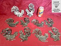 Five pairs of metal rooster wall decor pieces with a soda can for size reference on a red fabric background.