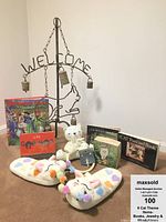Full display of all nine cat-themed items including books, slippers, bell wind chime, brooch, towel ring, and figurine