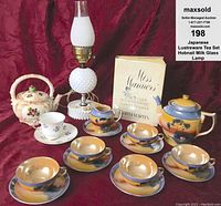 Full lot with tea set, lamp, book, and additional items against red fabric background