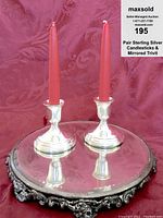 Candlesticks on top of the mirrored trivet with red taper candles, showing overall presentation with reflections.