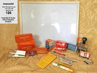 Photo showing whiteboard calendar, various stapler and staple boxes, pipe cleaners, stamp kits, and date stamper arranged with soda can for size comparison