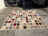 Full view of the large rectangular rug displaying its multicolor square pattern in natural light outdoors.