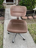 Front view of brown suede office chair showing padded seat and backrest, metal base with wheels.
