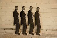 Four identical vintage cardboard stand-ups of Sean Connery against a brick wall.