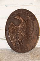 Close-up of the embossed eagle and text 'Eagle Hose No. 2' on the antique iron sign, showing detailed feather and claw work, and two mounting holes on sides.