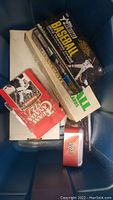 Blue plastic bin containing several sports card boxes and a red tin, top view shows Topps Heritage Baseball and Team Canada Hockey card boxes.