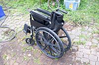 Folded wheelchair showing large rear wheels and folded frame.
