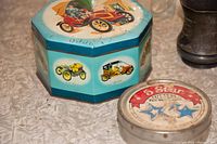 Close-up photo showing the blue octagonal tin with vintage car illustrations and the round 5 Star Cutters tin on a table surface