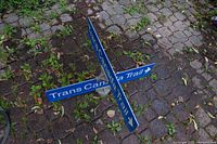 Photo showing the blue metal Trans Canada Trail sign with three perpendicular arms and white text.