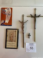 Top view of two novena prayer booklets, two medium and large crucifixes, small crucifix pendant, and auction lot tag.