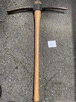Full view of a 36-inch railroad pick with a wooden hickory handle and metal head.