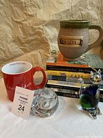 Two oversized mugs (one green with 'Cat Lover', one red with 'Crazy Cat Lady'), stacked cat-themed books, and two glass cat figurines plus clear glass candle holder.