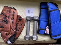 Photo showing Easton Natural Series brown leather baseball glove with visible wear and tear, with two small 3 lb dumbbells and two blue All Pro ankle weights.