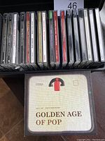 Photo shows a collection of assorted music CDs in jewel cases plus a 'Golden Age of Pop' CD in a cardboard sleeve.