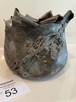 Front view of antique silver plate basket showing folded over tops and applied branch, flowers and bee decoration on side, with visible tarnish and wear.