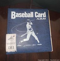 Blue 'Baseball Card Album' with a white silhouette of a baseball player hitting, shown closed.