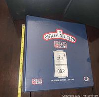 Photo of closed blue binder with 'The Official NFL Card' and NFL Pro Set logos on front cover and measuring tape beside it.