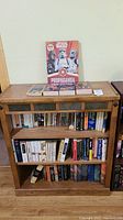 Full view of wooden bookshelf with three shelves containing various books, with 'Star Wars Propaganda' books displayed on top shelf