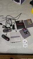 View of G-8 Bit HD console with two game controllers, Nintendo NES game cartridges, power and HDMI cables.