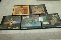 Full lot of five framed pictures laid out on a patterned white surface: two Indiana Jones and three Star Wars frames.
