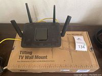 Linksys EA8300 router with four antennas placed on a box labeled 'Tilting TV Wall Mount'.