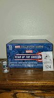 Front view of sealed Marvel Collector Corps Year of the Shield 5-piece mystery box with Captain America shot glass in front.