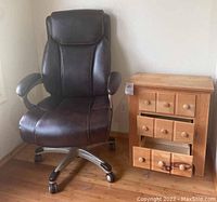 Office chair and nightstand side by side on wooden floor by wall corner