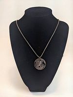 View of the necklace displayed on a black bust showing full length and shape of chain and pendant.