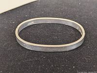 Sterling silver hinged bracelet with rectangular flat profile, showing the outer side and clasp.