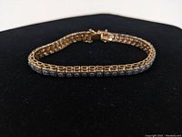 Photo of the gold plated sterling silver tennis bracelet showing front and side views, highlighting the linked square segments and clasp.