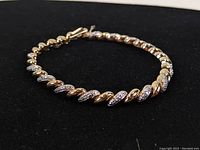 Image of the twisted bracelet showing the gold plated and stone-studded link design on black background.