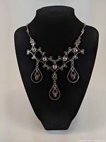 Full view of the sterling silver necklace displayed on a black bust, showing the overall design and three tiger eye stone pendants.