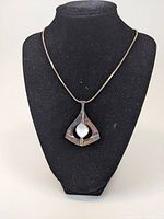 Full view of pendant and chain displayed on black bust stand showing shape and length