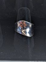 Front view of modernist sterling silver ring with a smooth polished surface showing reflection and minor wear.