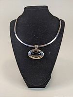 Front view of the necklace displayed on black mannequin bust showing sterling collar and oval black onyx pendant.