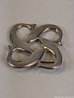 Top-down view of a sterling silver brooch with an abstract looping design.