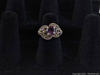 Front view of sterling silver ring with marcasite and amethyst colored stone on black display, showing the stone and marcasite details.