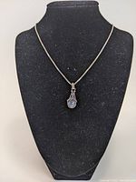 Front view of necklace displayed on black velvet stand showing the teardrop pendant with milky blue stone and sterling silver detailing.