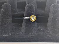 Front view of sterling silver solitaire ring with yellow cushion-cut stone on display stand.