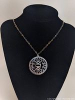Full view of the sterling silver chain necklace with the round reticulated pendant displayed on a black bust.
