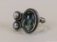 Angle view of sterling silver ring highlighting the green stone and two pearls with rope-edge bezel setting.