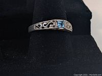 Front and top view of sterling silver ring with openwork design and pale blue square stone.