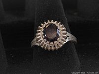 Close-up image of the sterling silver ring with an oval faceted amethyst colored stone in a crown-like bezel setting, showing details and condition.