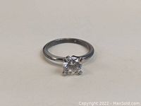 Front view of sterling silver ring with solitaire clear stone on plain background.
