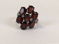 Front view of the sterling silver cluster ring with seven oval red stones.