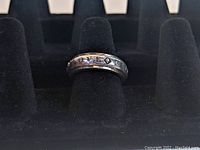 Sterling silver ring showing the 'Love' engraving on the spinning outer band, displayed on a black ring holder.