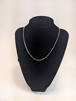 Full front view of the sterling silver triple strand necklace displayed on a black velvet bust stand.