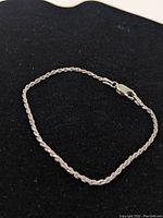 Photo of the sterling silver twisted rope bracelet laid flat on black background showing full length and design.